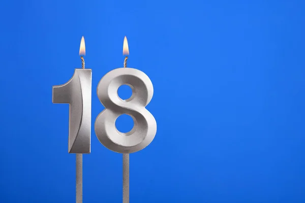 Birthday number 18 - Candle lit on blue background