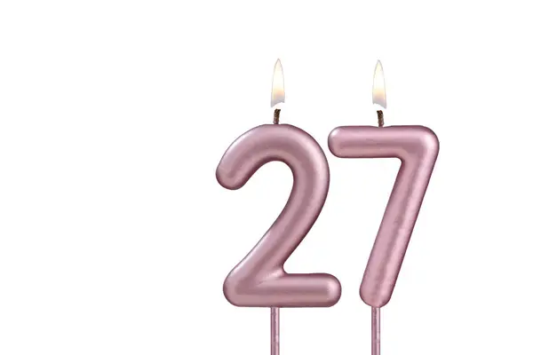 Candle number 27 - Lit birthday candle on white background