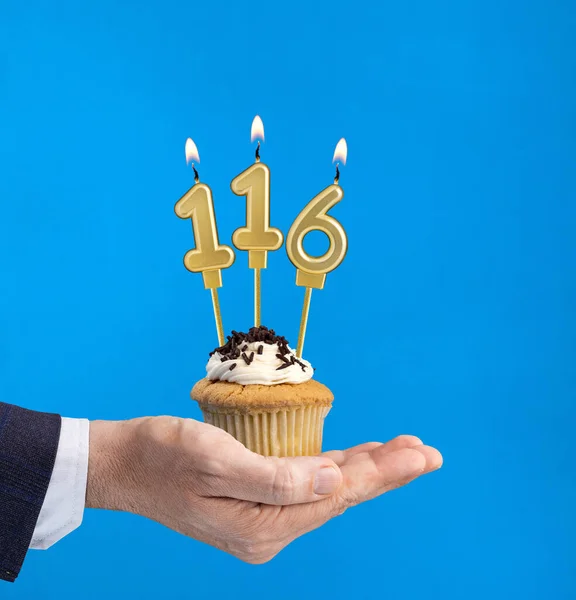 Hand delivering birthday cupcake - Candle number 116 on blue background