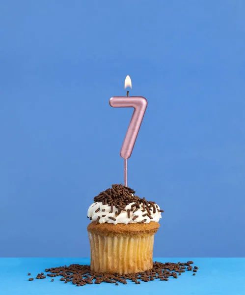 Birthday candle with cupcake on blue background - Number 7