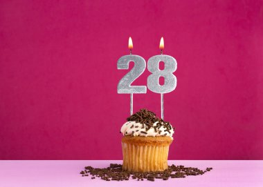 28 numaralı mumla doğum günü kutlaması - Pembe arka planda çikolatalı kek