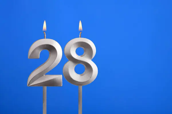 Birthday number 28 - Candle lit on blue background