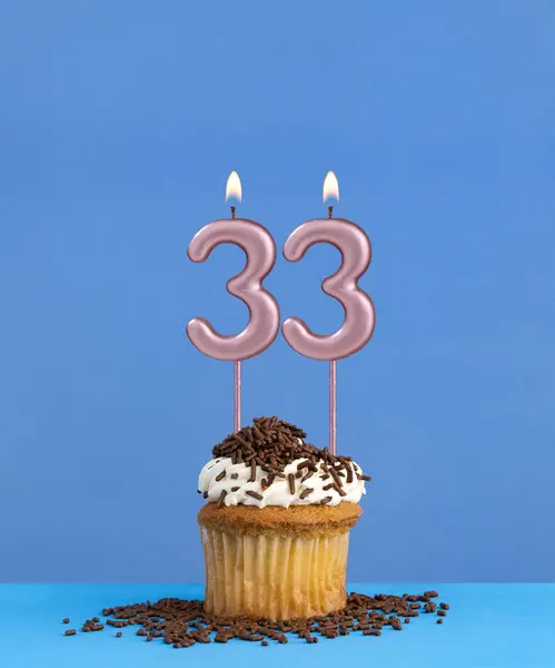 Birthday candle with cupcake on blue background - Number 33