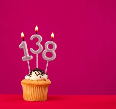 138 numaralı mum. Rodamine kırmızı arka planda cupcake doğum günü.