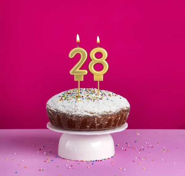 stock image Lighted birthday candle number 28 - Birthday card on pink background