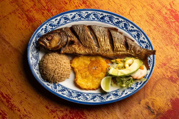 Fried anchovy fish with coconut rice, patacon and vegetable salad