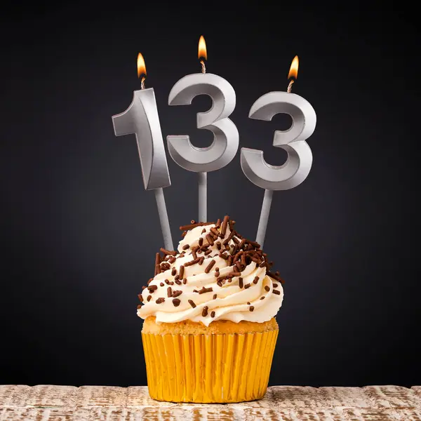 Birthday candle number 133 - Anniversary cupcake on black background
