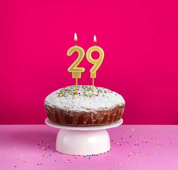 Birthday cake with number 29 candle on pink background