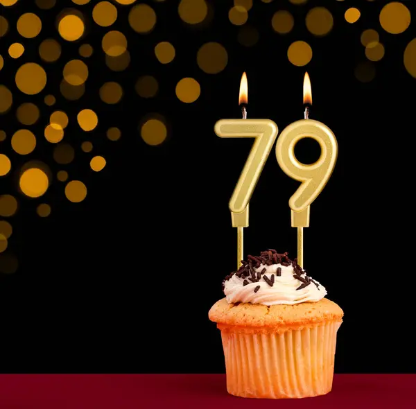 stock image Number 79 birthday candle - Cupcake on black background with out of focus lights