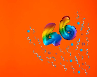 46 numaralı çoklu renkli balon turuncu arka planda konfeti patlaması. Doğum günü kartı