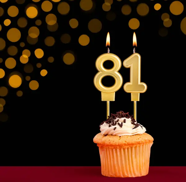 stock image Number 81 birthday candle - Cupcake on black background with out of focus lights