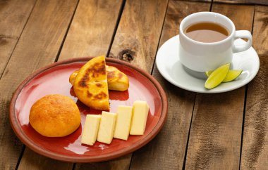Colombian food - Arepa boyacense for breakfast, accompanied with cheese, almojabana and aguapanela with lemon clipart