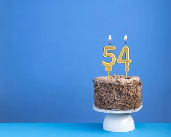 キャンドル54の誕生日ケーキ 青い背景に招待カード ストックフォト