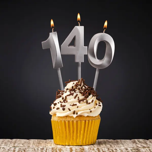 140本のキャンドルを持つ誕生日カップケーキ 暗い背景でお祝い ストック写真