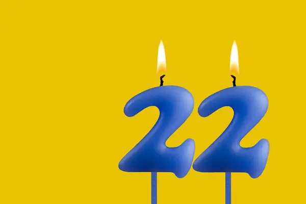 stock image Blue candle number 22 - Birthday on yellow background