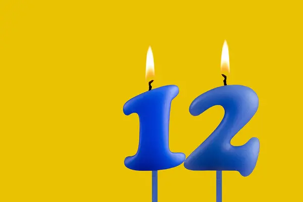 stock image Blue candle number 12 - Birthday on yellow background