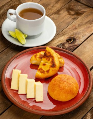 Traditional Boyaca breakfast - Arepa, almojabana, cheese and hot aguapanela clipart