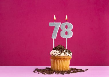 78 numaralı mumla doğum günü kutlaması - Pembe arka planda çikolatalı kek