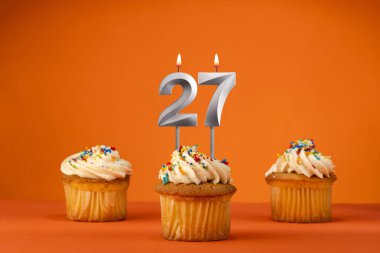 27 numaralı mum - turuncu arka planda doğum günü keki ile kutlama
