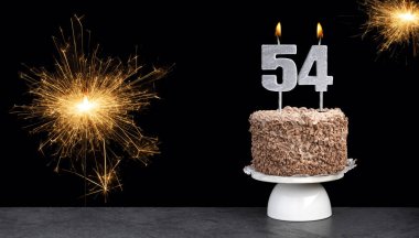 Pasta ve 54 numaralı mumla doğum günü kutlaması.
