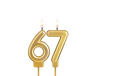 Beyaz arkaplanda 67 numaralı doğum günü mumu.