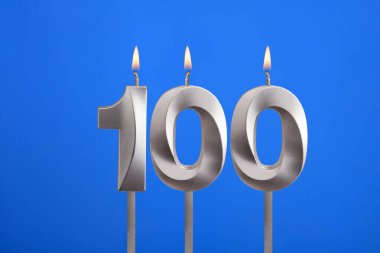 100 numaralı doğum günü - Mavi arkaplanda mum yanıyor