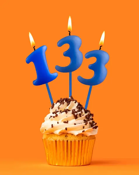 stock image Blue candle number 133 - Birthday cupcake on orange background