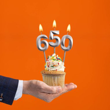 650 mumlu keki teslim eden el - turuncu arka planda doğum günü