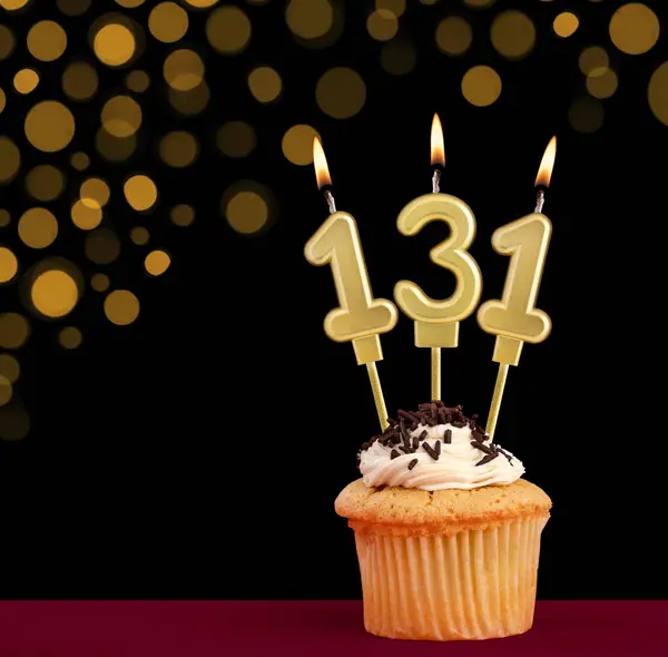 stock image Number 131 birthday candle - Cupcake on black background with out of focus lights