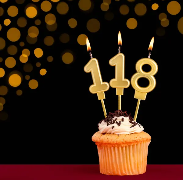 stock image Birthday candle with cupcake - Number 118 on black background with out of focus lights