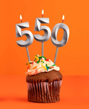 550 numara mum turuncu arka planda doğum günü pastası.