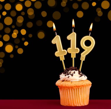 119 numara doğum günü mumu - Siyah arka planda kek ve odak ışıkları yok