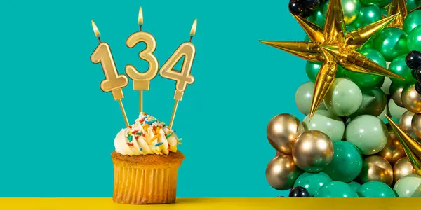 stock image Birthday candle number 134 - Cupcake with decoration on a green background