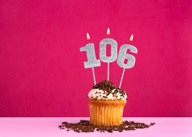 106 numaralı mumla doğum günü kutlaması - Pembe arka planda çikolatalı kek