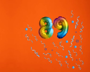 89 numaralı balonla konfeti patlaması turuncu arka planda kutlama. Doğum günü kartı