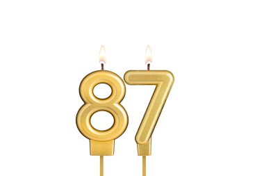 Beyaz arkaplanda 87 numaralı doğum günü mumu.