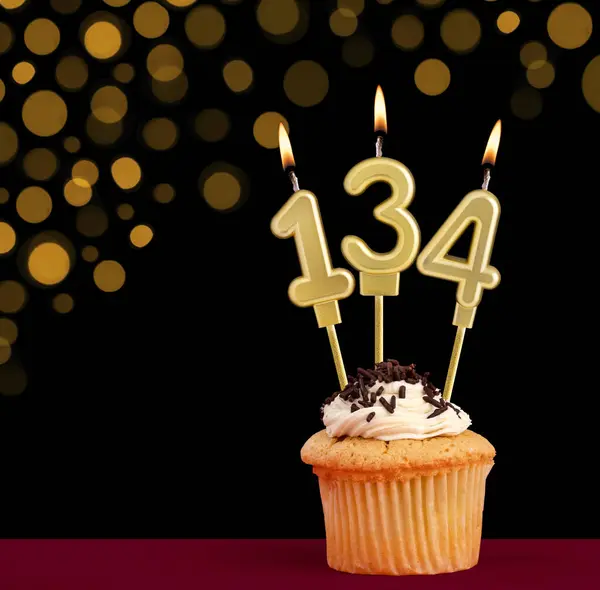 stock image Birthday candle with cupcake - Number 134 on black background with out of focus lights