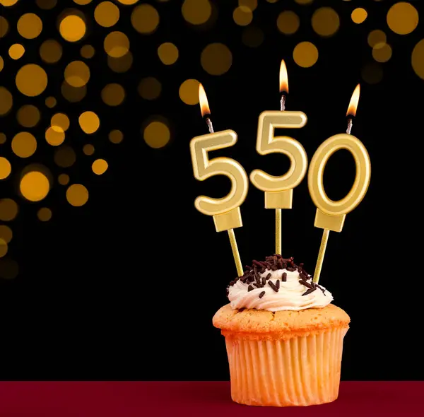 stock image Birthday candle with cupcake - Number 550 on black background with out of focus lights