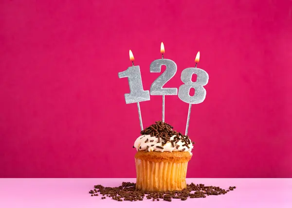 Stock image Birthday celebration with candle number 128 - Chocolate cupcake on pink background