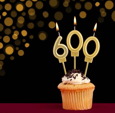600 numaralı doğum günü mumu - Siyah arkaplanlı ve odak ışıkları olmayan kek