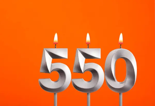 stock image 550 candle - Birthday celebration on orange background