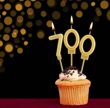 700 numaralı doğum günü mumu - Siyah arkaplanlı ve odak ışıkları olmayan kek