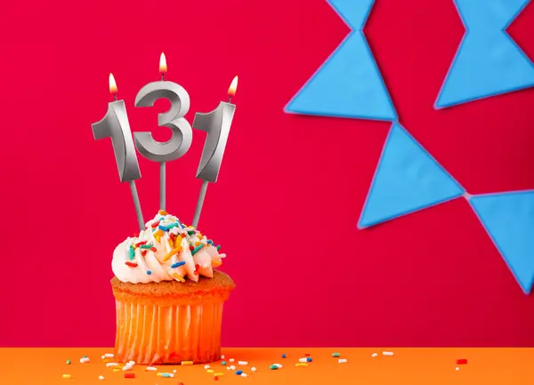 Stock image Number 131 candle with birthday cupcake on a red background with blue pennants