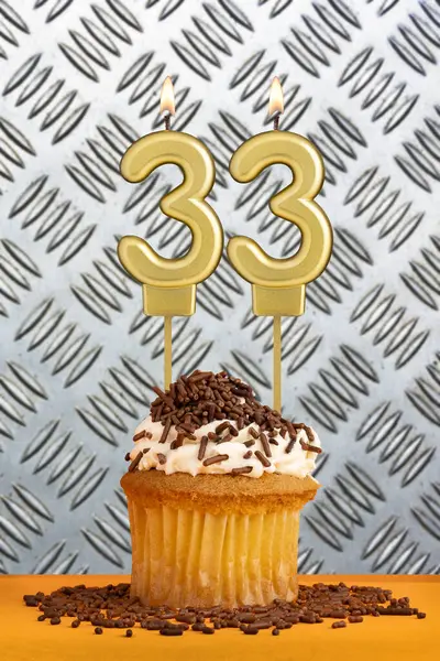 stock image Chocolate cupcake with candle number 33 - Birthday on industrial metallic background.