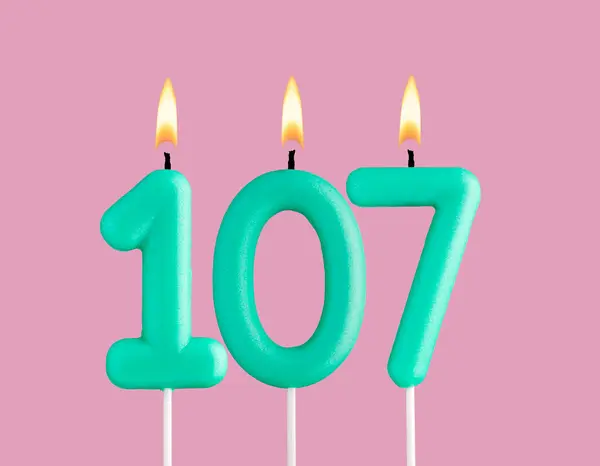 stock image Birthday card with green number 107 candle - Pastel pink background