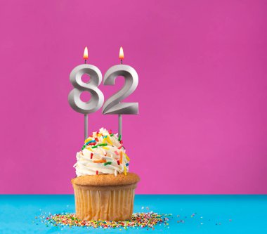 82 numaralı doğum günü mumu - menekşe ve mavi arka planda kutlama kartı