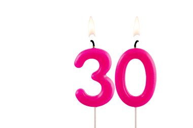 30 numaralı pembe doğum günü mumu beyaz arkaplanda yanıyor.