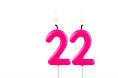 Pembe numara 22 doğum günü mumu beyaz arkaplanda yanıyor