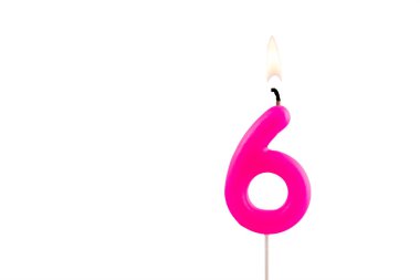 Pembe 6 numaralı doğum günü mumu beyaz arkaplanda yanıyor.