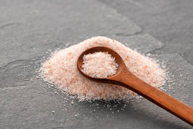 Tahta kaşıkta ince pembe Himalaya tuzu - ince kristaller serpiştirilmiş.